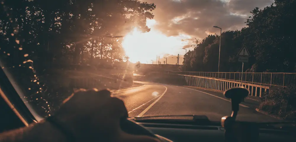 Man driving car toward the sunset