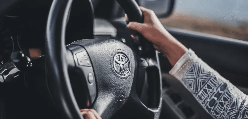 women turning steering wheel with Toyota logo