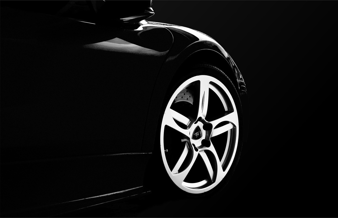 Close-up of a shiny alloy wheel and tire on a dark car