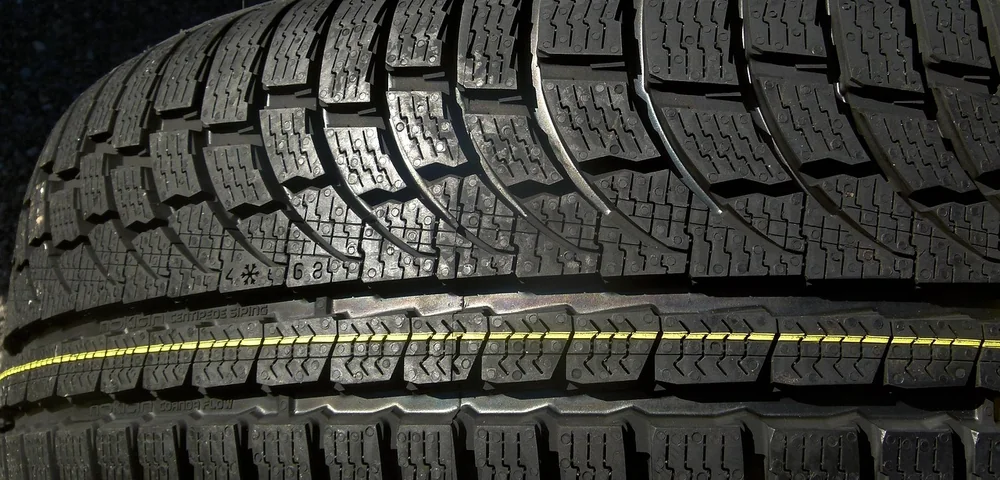 Close-up of a tire tread with deep grooves, showing detailed pattern designed for traction.