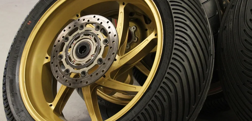Close-up of a gold motorcycle wheel with a fresh tire showing detailed tread pattern