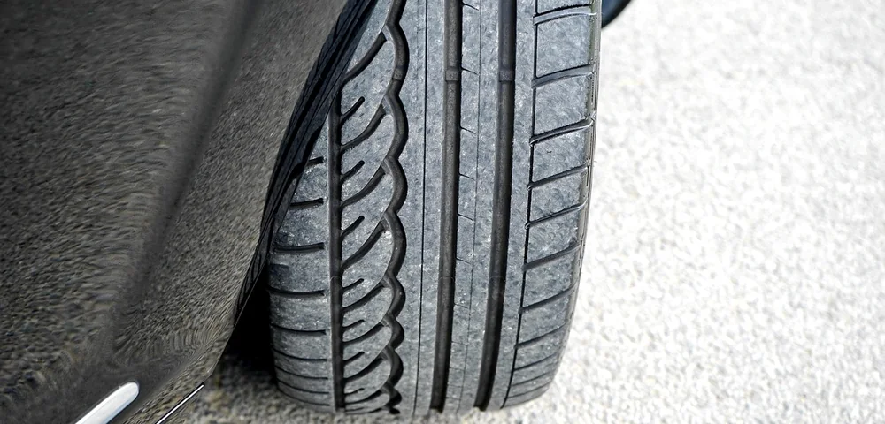 Close-up of a car tire tread on pavement, showing detailed grooves and pattern.