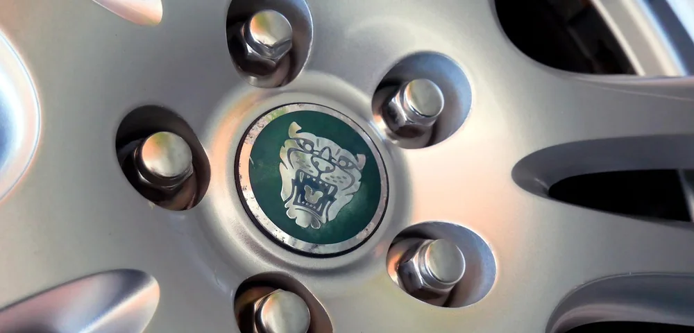 Close-up of a car wheel showing lug nuts arranged in a circular bolt pattern around the center cap.