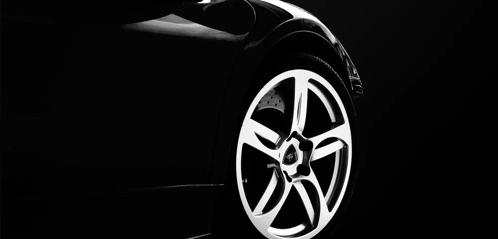 Close-up of a car's alloy wheel and tire sidewall against a dark background