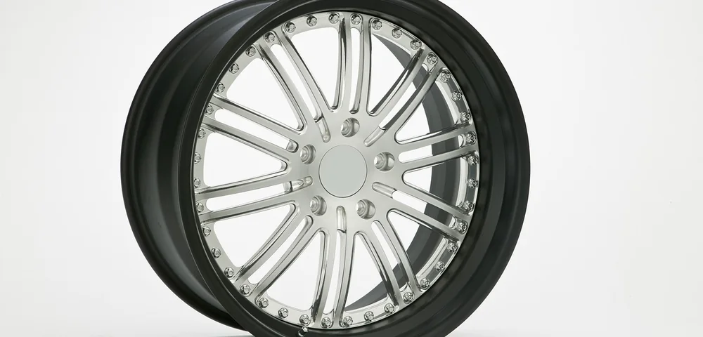 Close-up studio photo of a chrome and black alloy wheel with a mounted tire