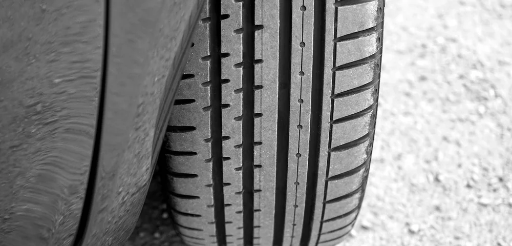 Close-up of a car tire tread on gravel pavement