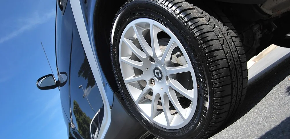 Close-up of a car's tire and alloy wheel against a clear blue sky.