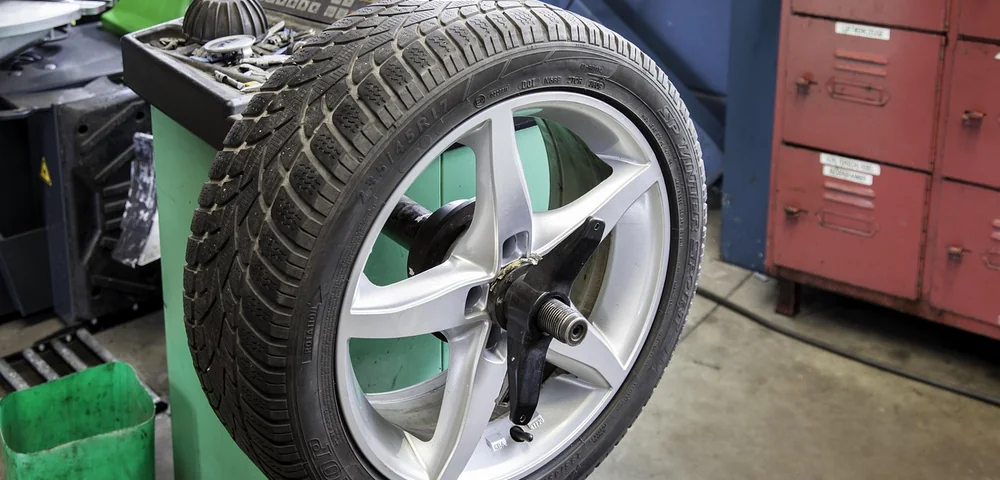 A tire mounted on a wheel balancing machine in a repair shop.
