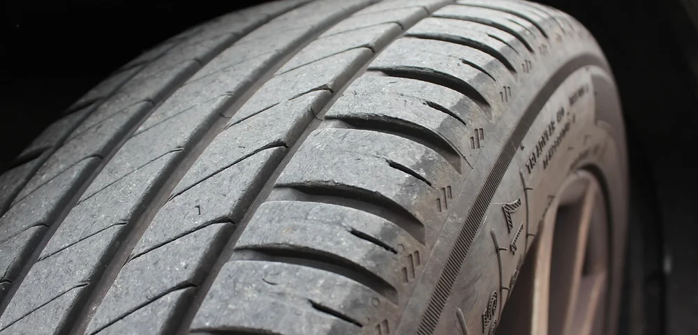 Close-up of a car tire tread showing grooves and sidewall detail.