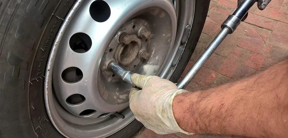 Mechanic using a lug wrench to remove a car wheel during a tire rotation