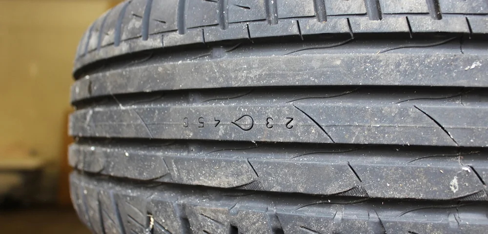 Close-up of a car tire tread showing worn, angled tread blocks indicative of feathering wear.
